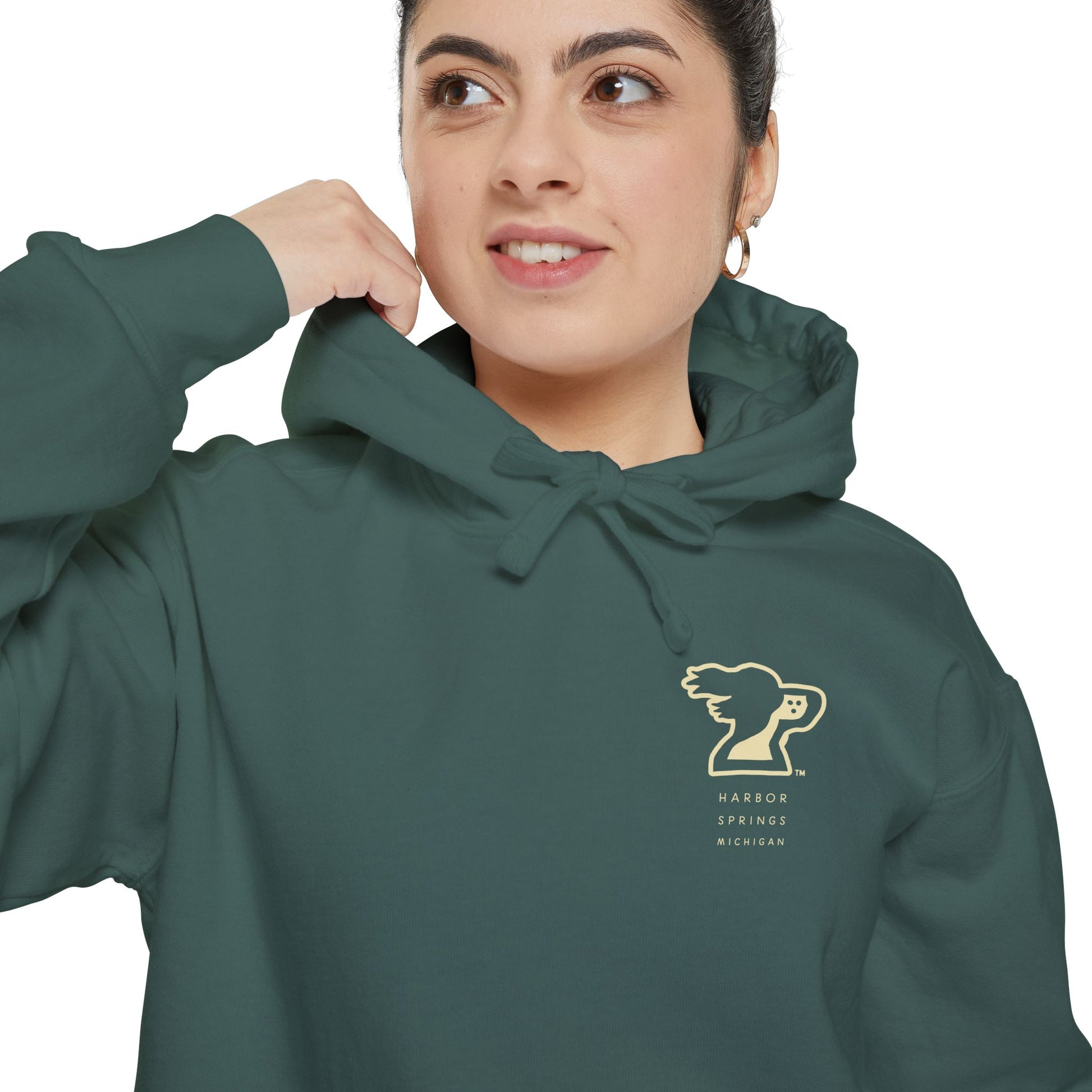 Woman wearing a green color hoodie by the Harbor Springer brand with a springer spaniel dog logo and Harbor Springs Michigan text.