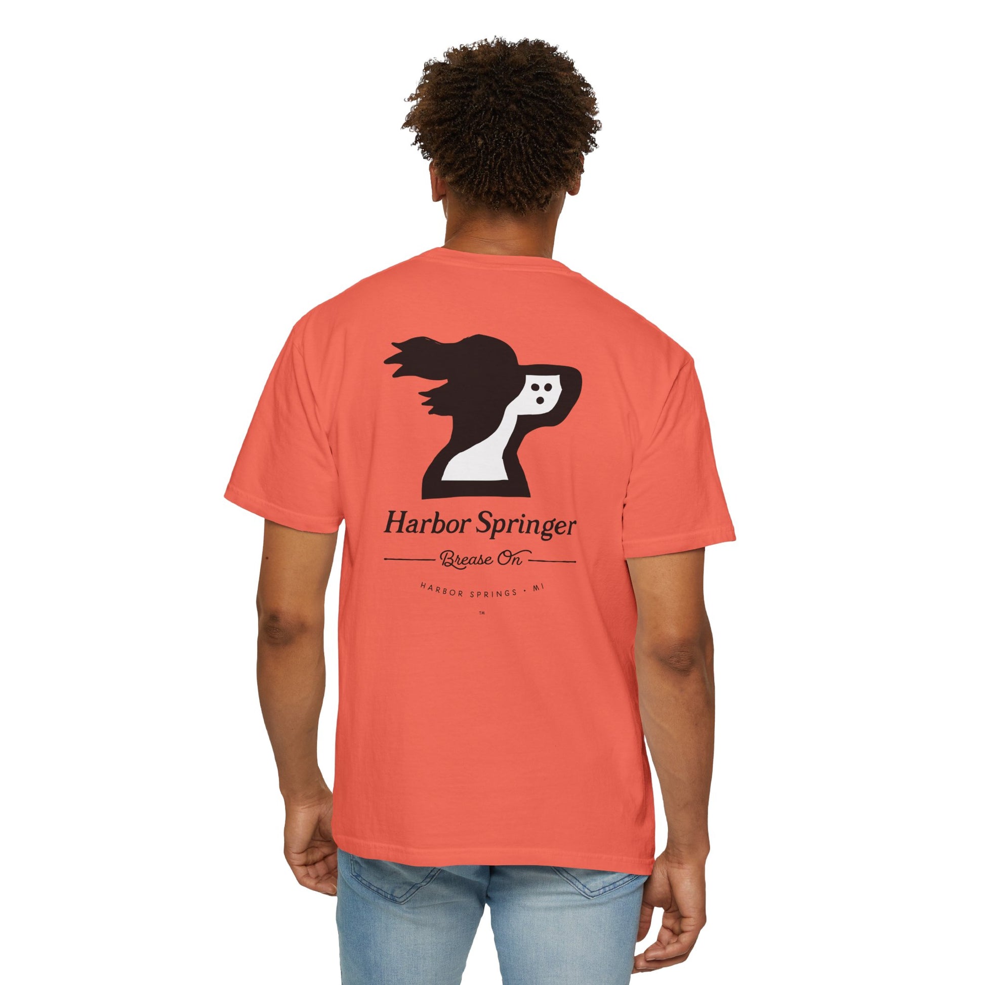 Standing man wearing salmon color t-shirt by the Harbor Springer brand with a springer spaniel dog logo and Brease On tagline on the back.