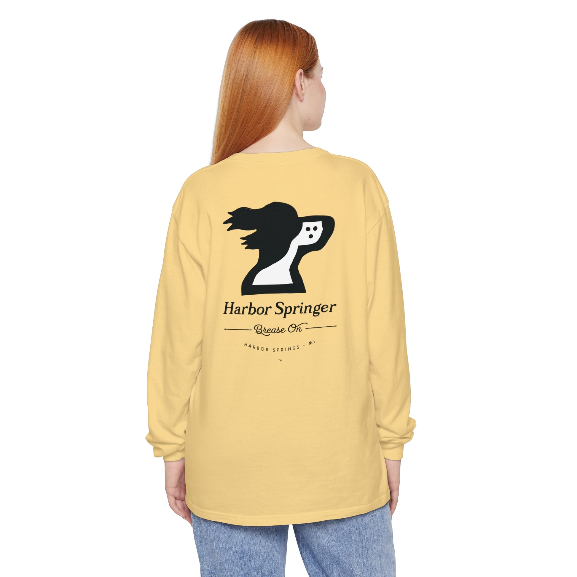 Woman wearing a light yellow long sleeve t-shirt by the Harbor Springer brand with a springer spaniel dog logo and Brease On tagline on the back.