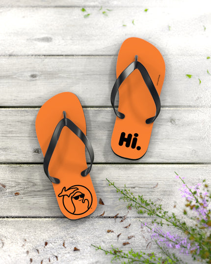 Michigan flip-flops in orange with black straps on a wood floor.