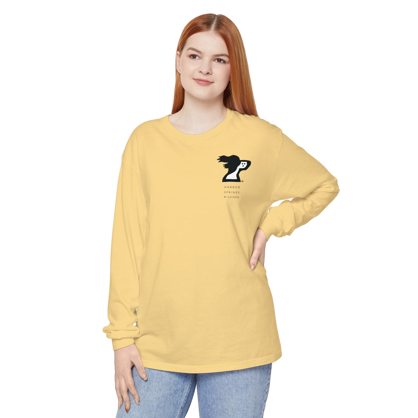 Woman standing nand wearing a light yellow color long sleeve t-shirt by the Harbor Springer brand with a springer spaniel dog logo and Harbor Springs Michigan text.