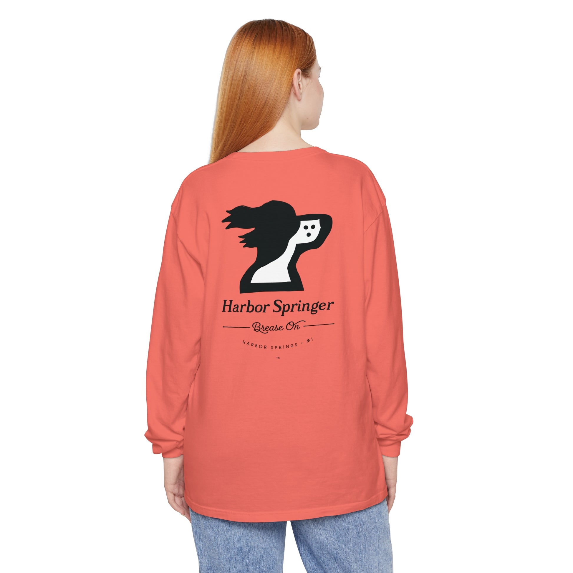 Woman wearing a salmon color long sleeve t-shirt by the Harbor Springer brand with a springer spaniel dog logo and Brease On tagline on the back.