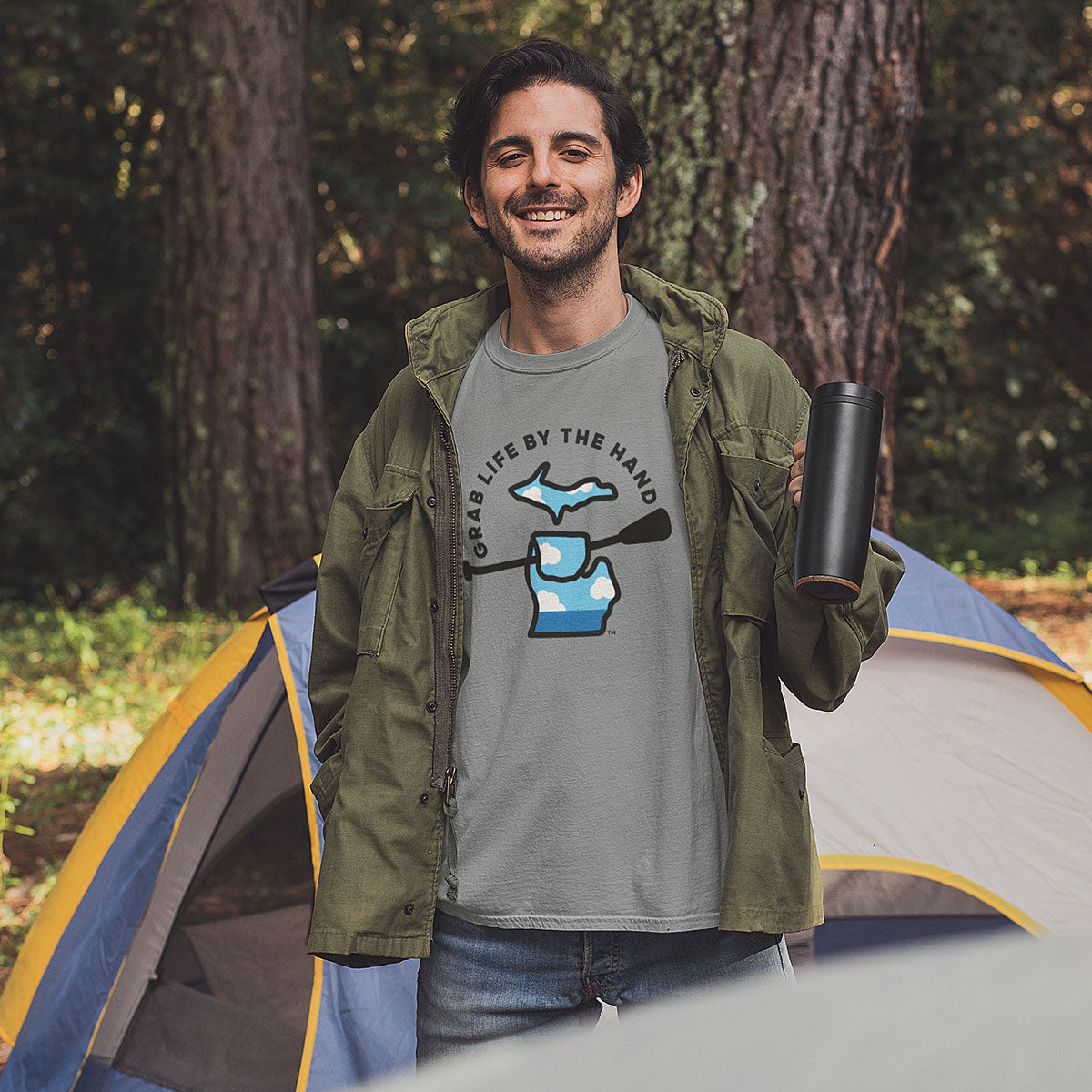 Camping man wearing a Michigan tee for people who kayak, canoe or paddleboard, showing the state of Michigan grabbing a paddle with the slogan Grab Life by the Hand™.