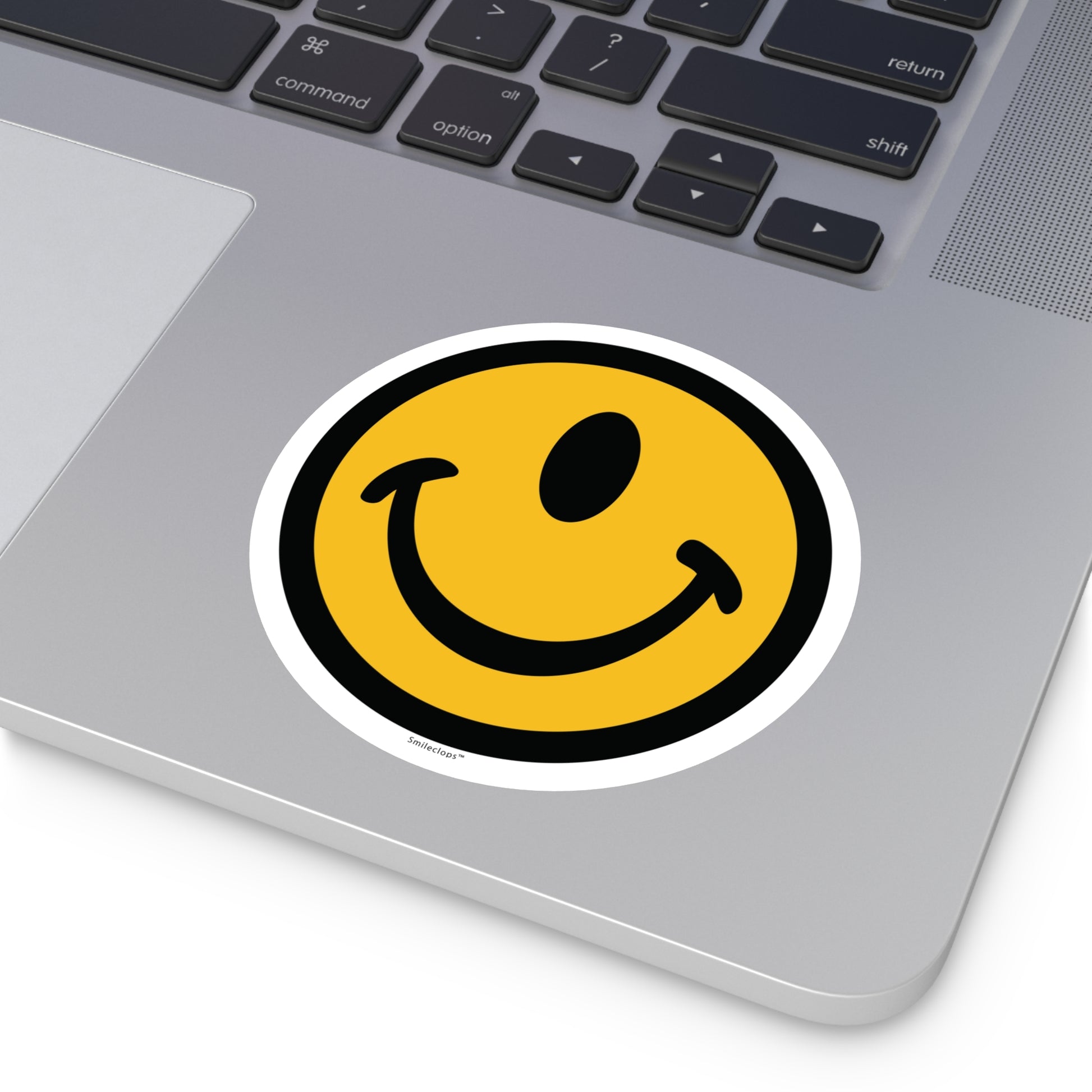 Large one-eyed smile face round sticker by the Smileclops™ brand on a laptop.