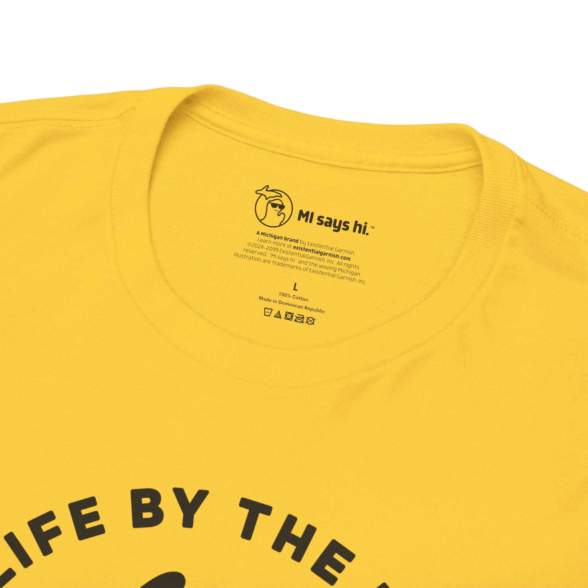 Closeup of neck label of a yellow Michigan tee for people who kayak, canoe or paddleboard, showing the state of Michigan grabbing a paddle with the headline Grab Life by the Hand™.