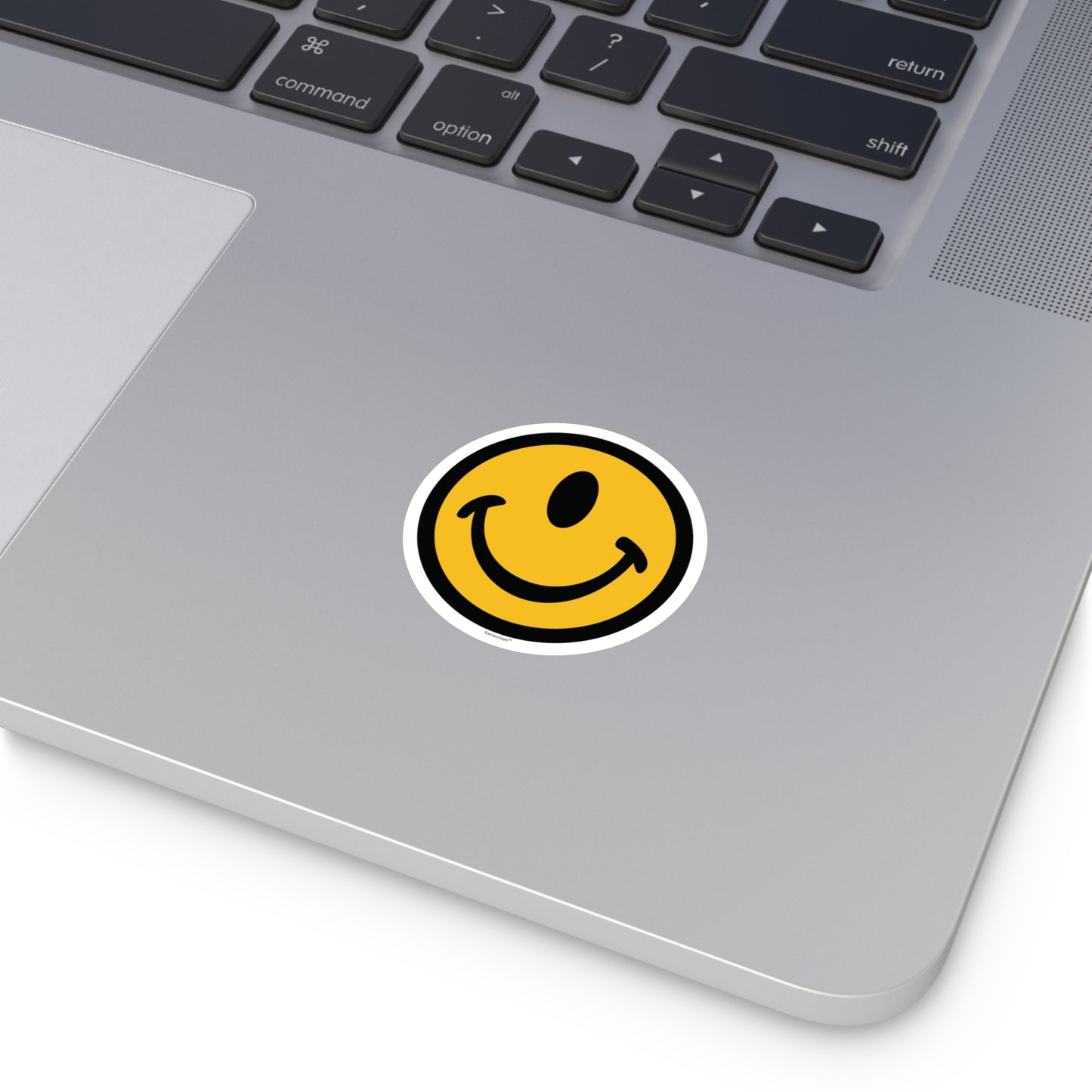 One eyed smile face round sticker by the Smileclops™ brand on a laptop.