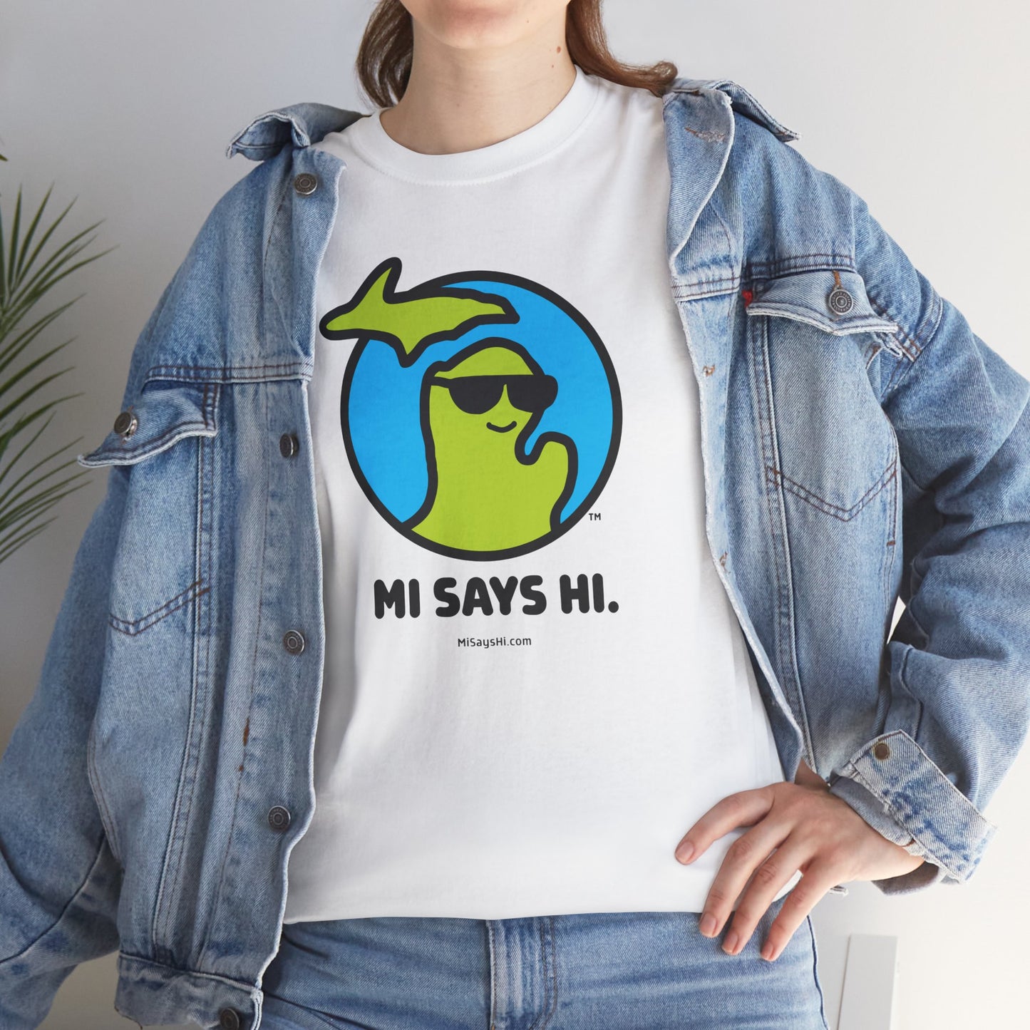 Woman wearing a white cotton t-shirt with a waving Michigan logo wearing sunglasses and smiling for the MI Says Hi brand.